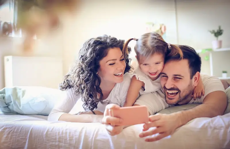 A happy family relaxing together on their bed at home